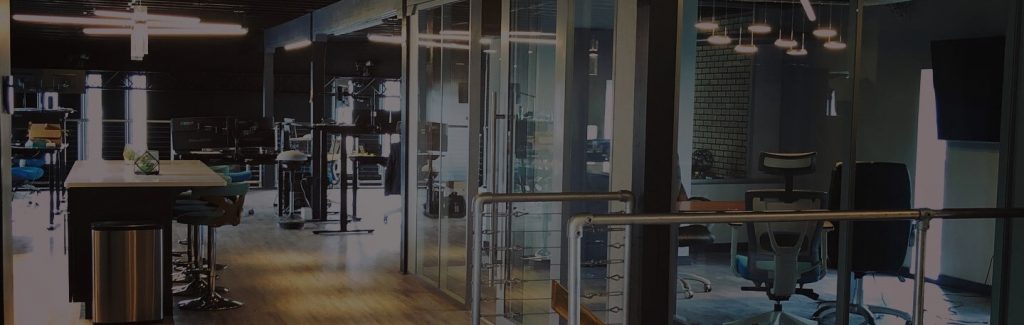 The Inside Of An Office Building With Glass Dividers And White Lights.